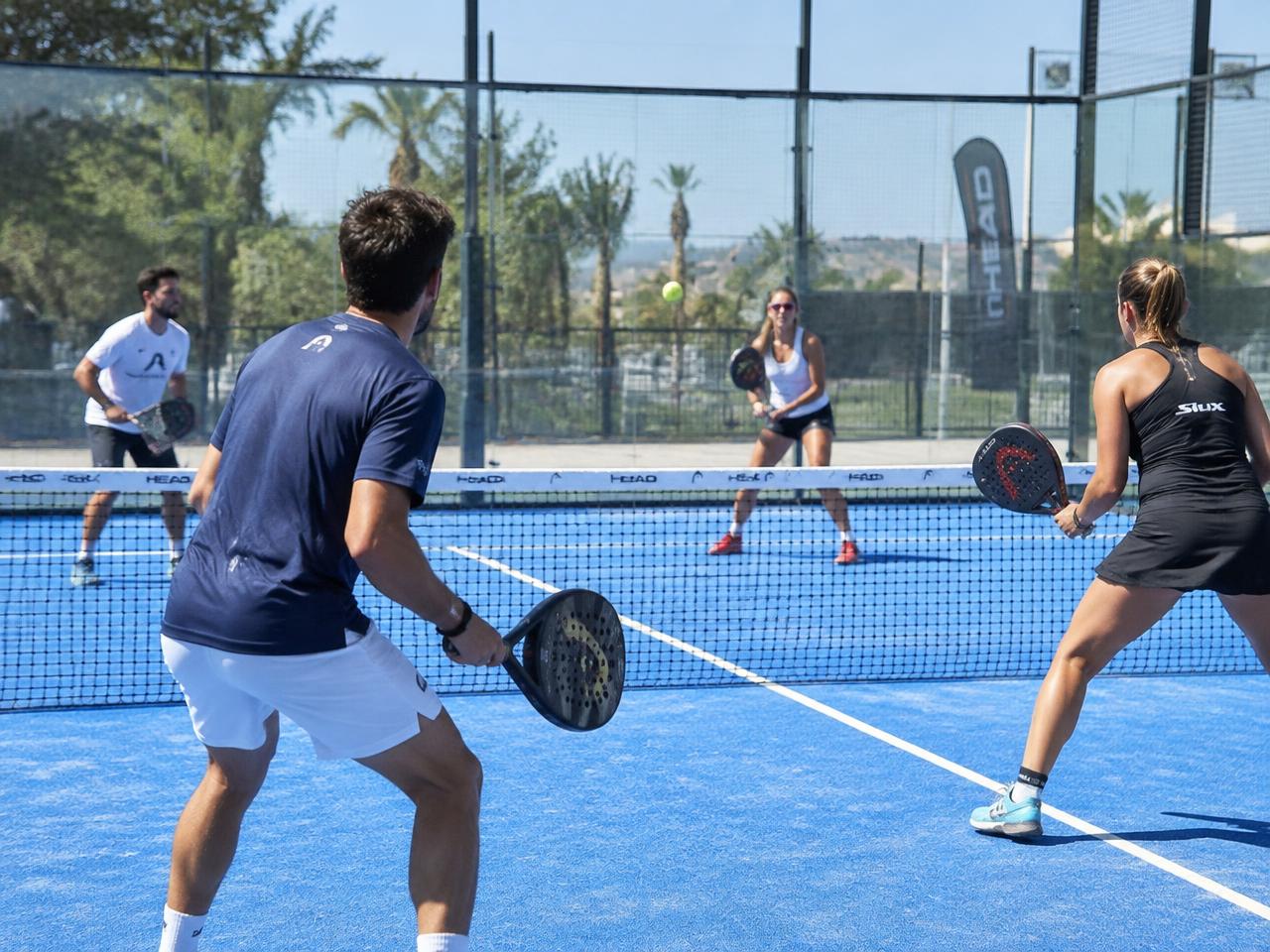 Players in a padel doubles match on a blue court